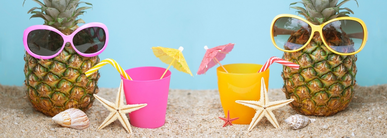 Twee ananassen met zonnebril op het strand aan het drinken