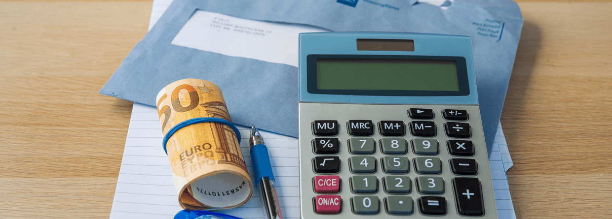 close up van een rekenmachine, rolletje geld van 50 euro, pen, kladblok en een brief van de Belastingdienst