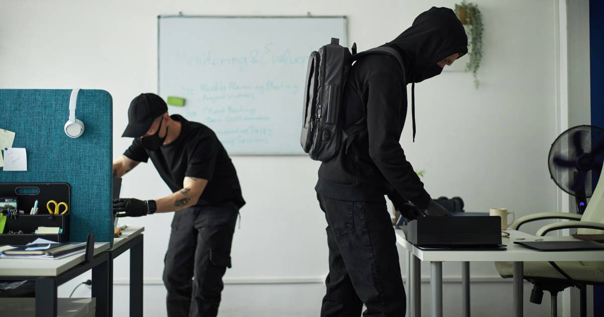Twee inbrekers in zwarte kleding doorzoeken een kantoor